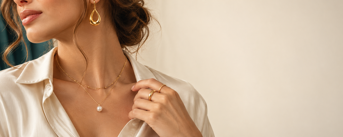 Model wearing layered necklaces, earrings and rings